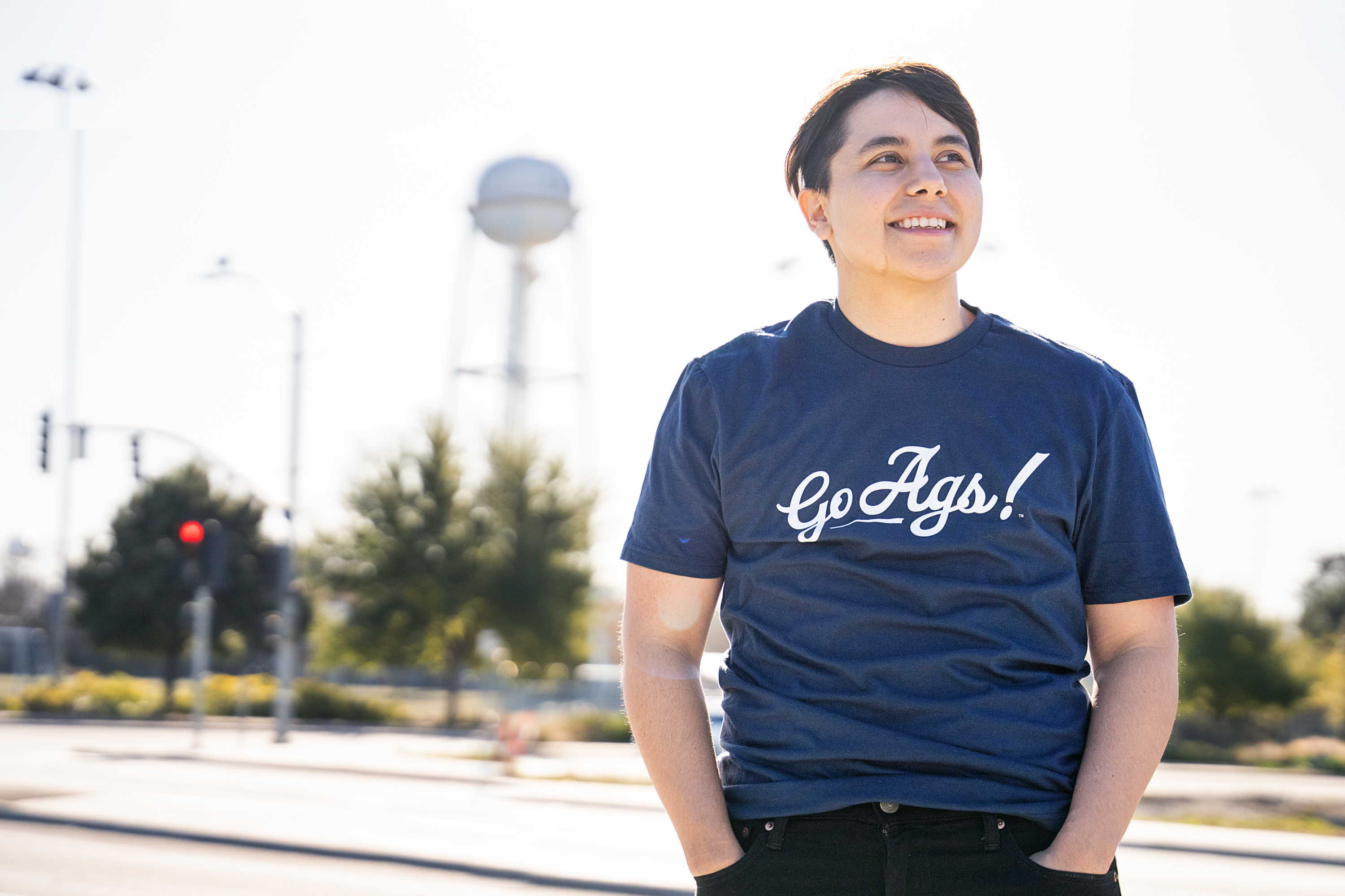 Employee wearing Go Ags! T-shirt with campus water tower in the background